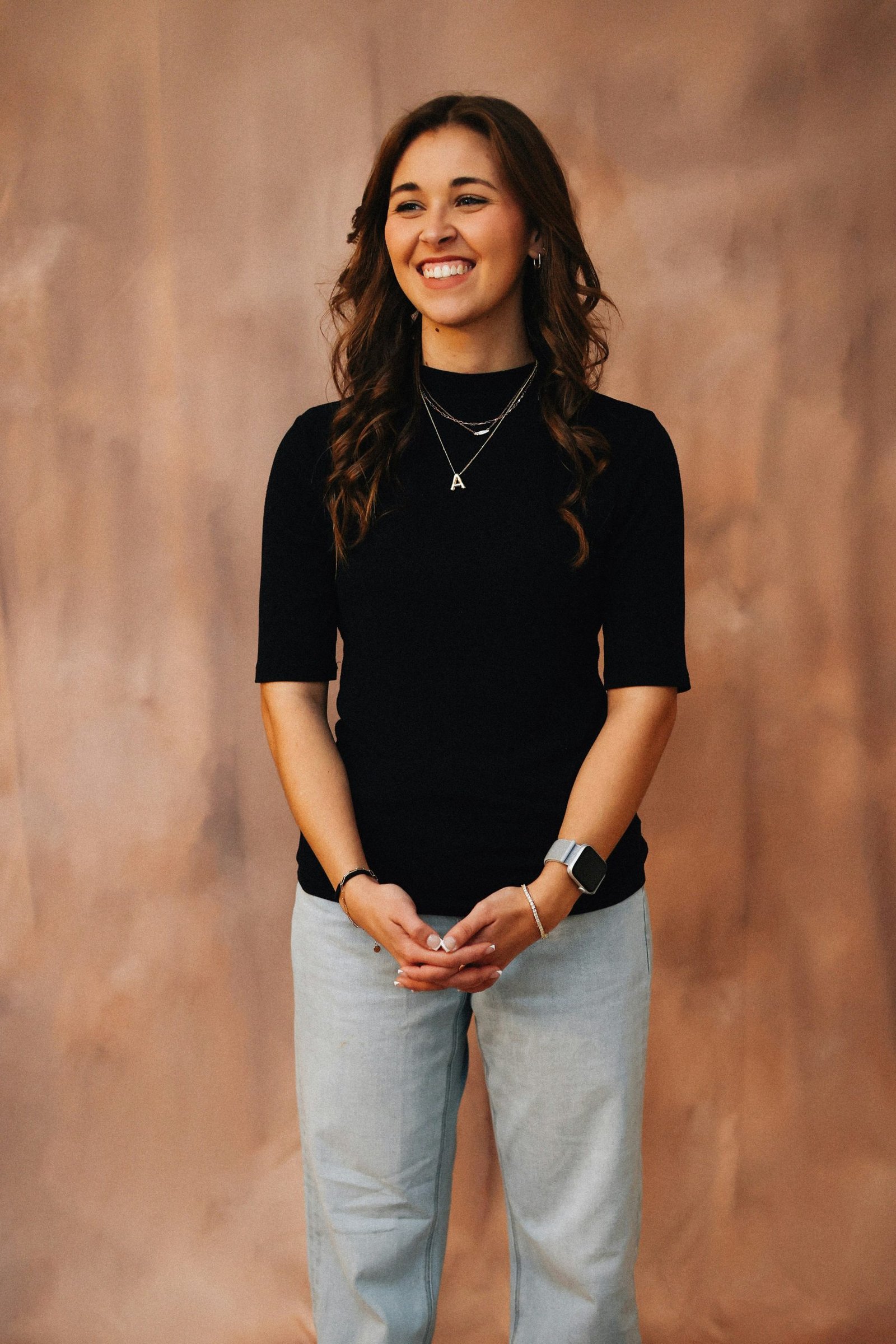 Dark haired women smiling and standing looking away from camera